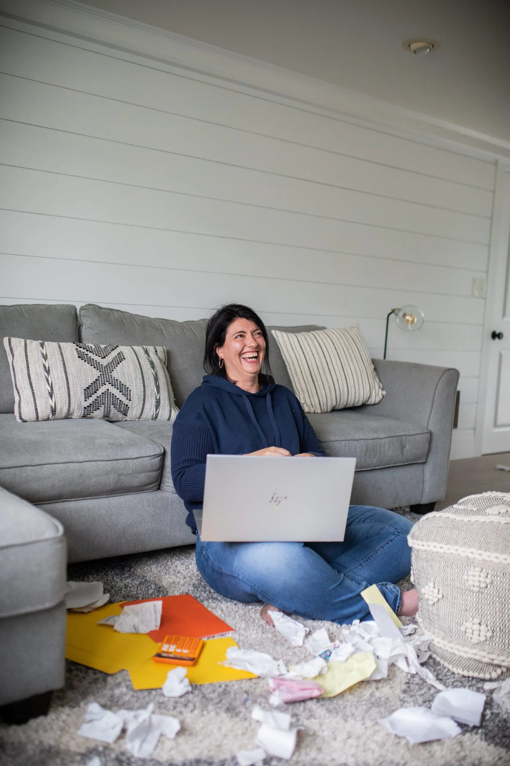 Michelle Murphy laughing while working on a laptop, surrounded by scattered paperwork